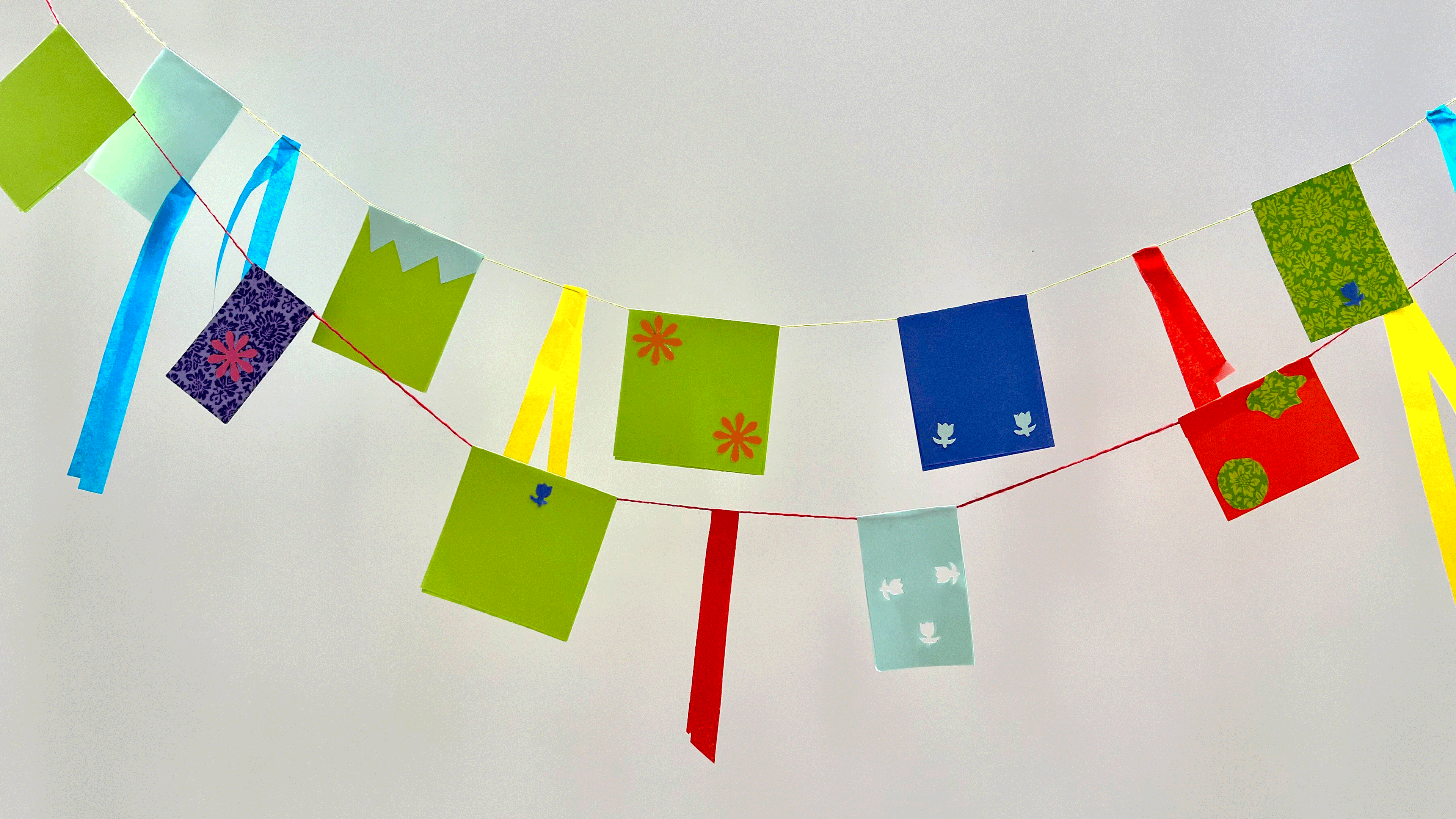 Eine bunte Wimpelkette aus Papier ist vom linken zum rechten Bildrand gespannt.