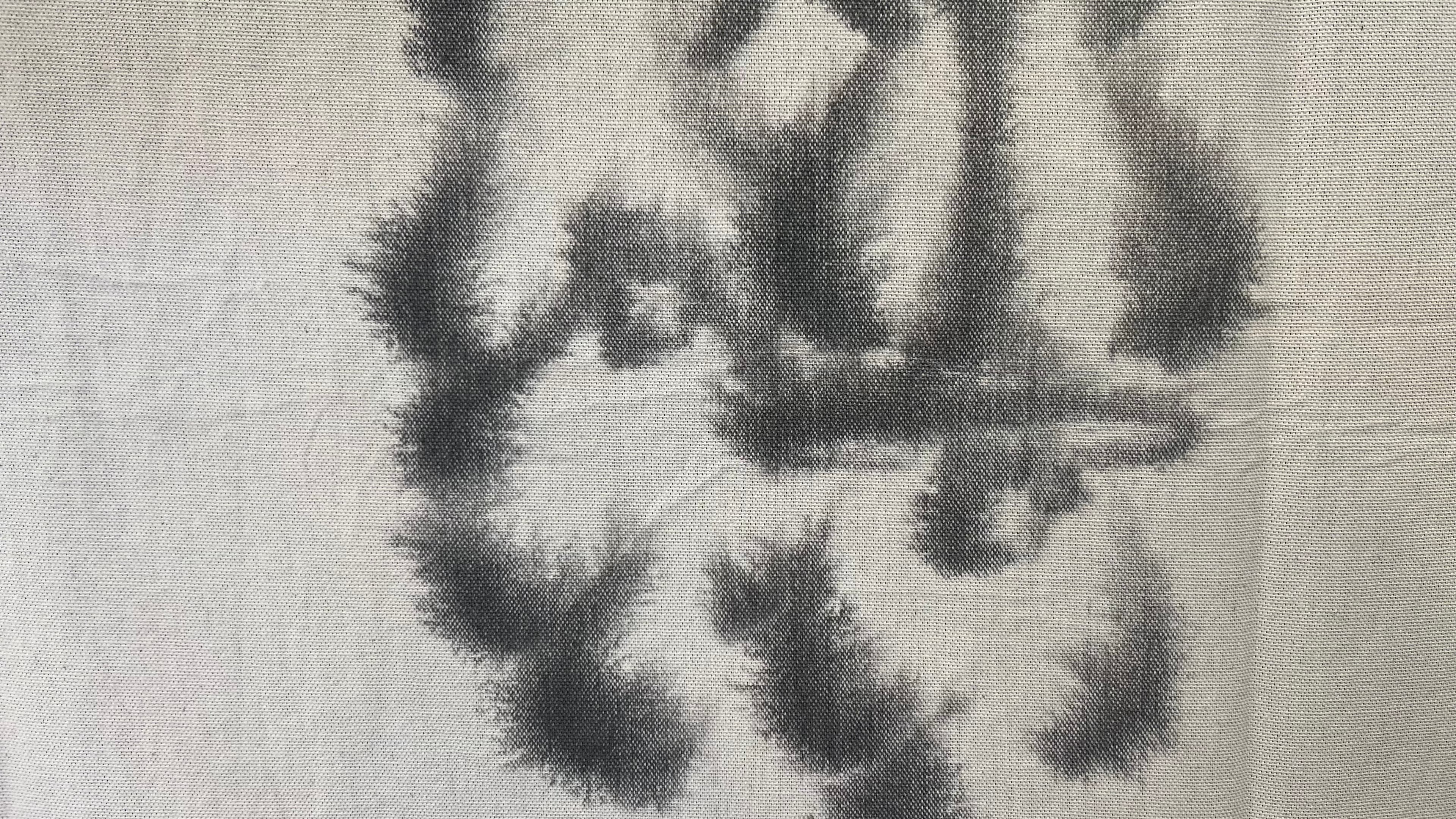 Auf einem Textilstoff sind im Detail schwarze Farbverläufe von Tusche zu sehen