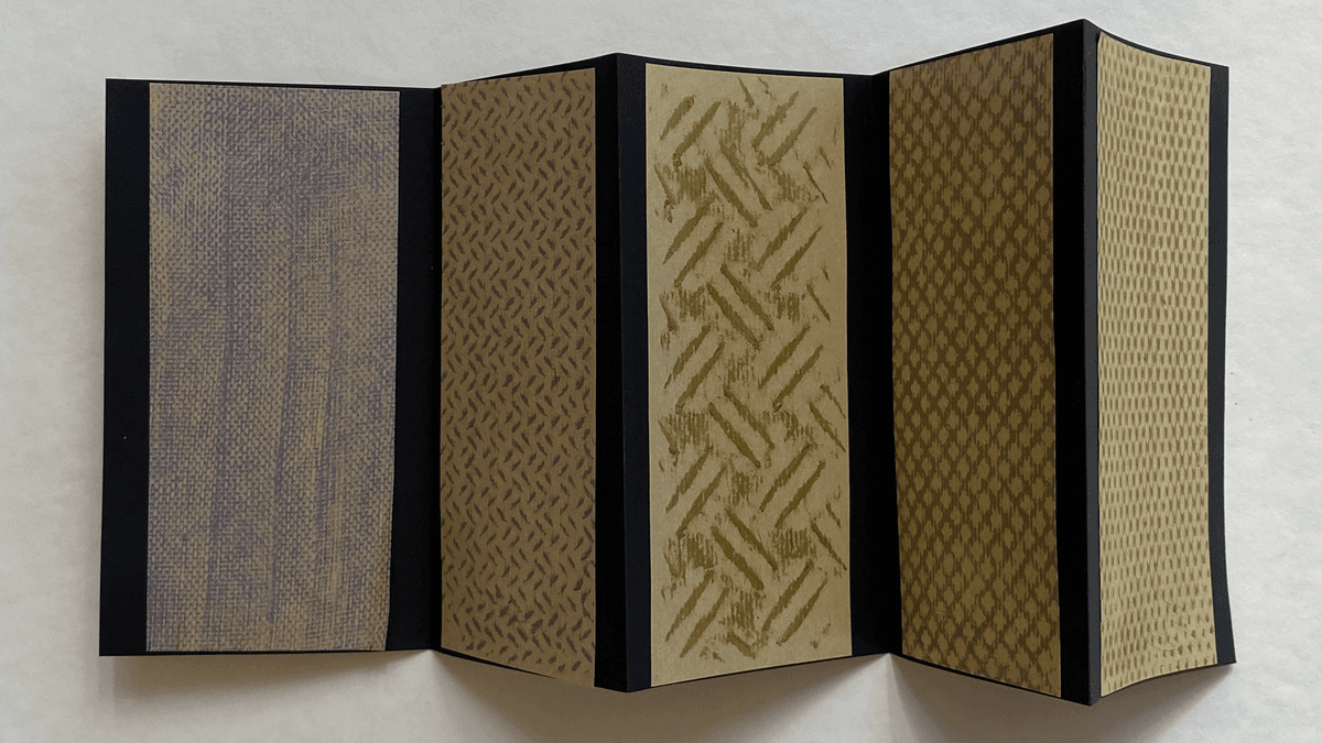 Ein aufgeklapptes Künstler:innenbuch mit Drucken in goldener Farbe