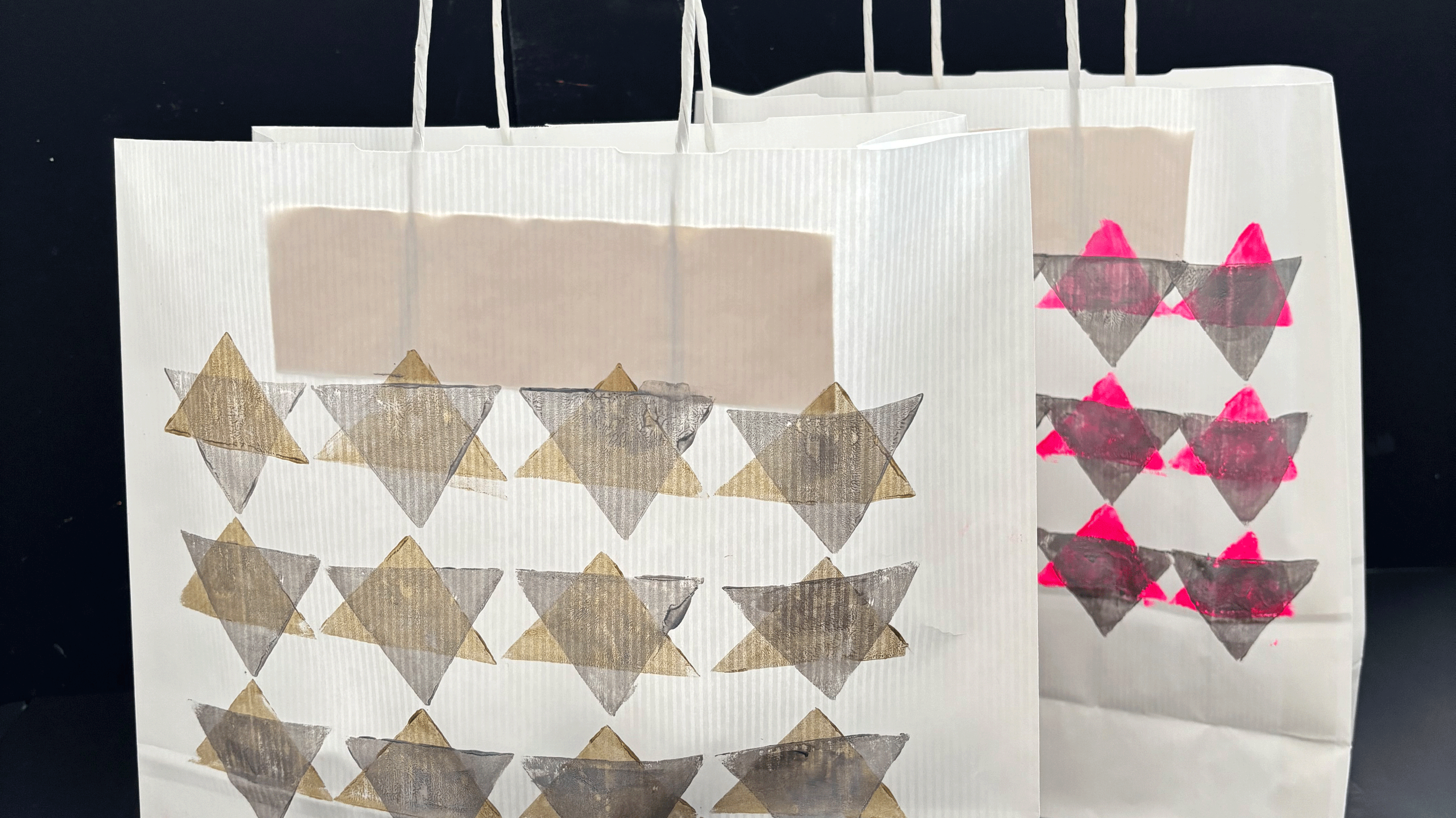 Auf zwei weissen Papiertüten sind in geometrischen Formen Muster gestempelt.