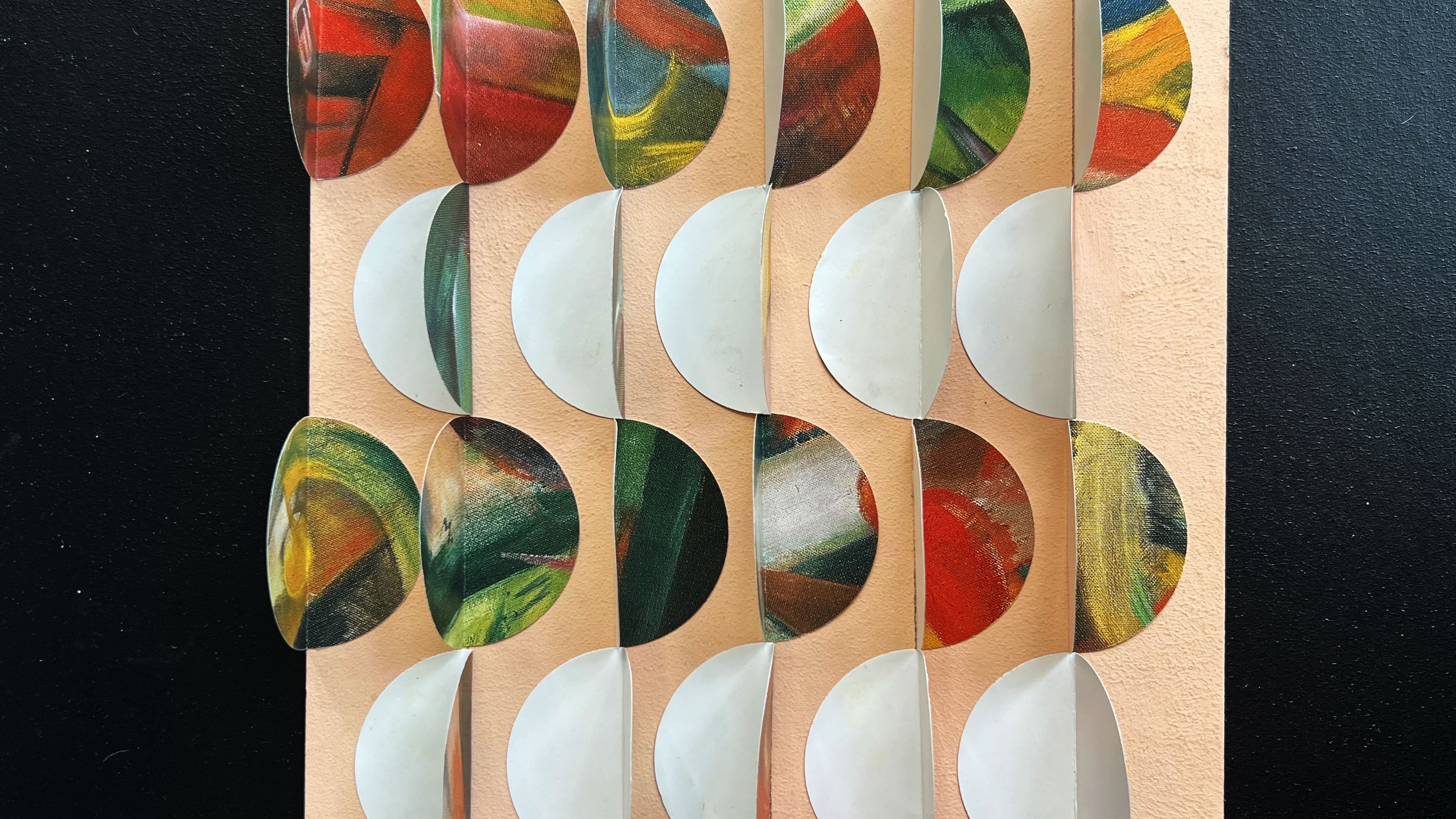 Ein selbstgestaltetes Kunstwerk aus gestanzten Punkten aus Papier auf einem orangefarbenen Hintergrund in Reihen arrangiert.