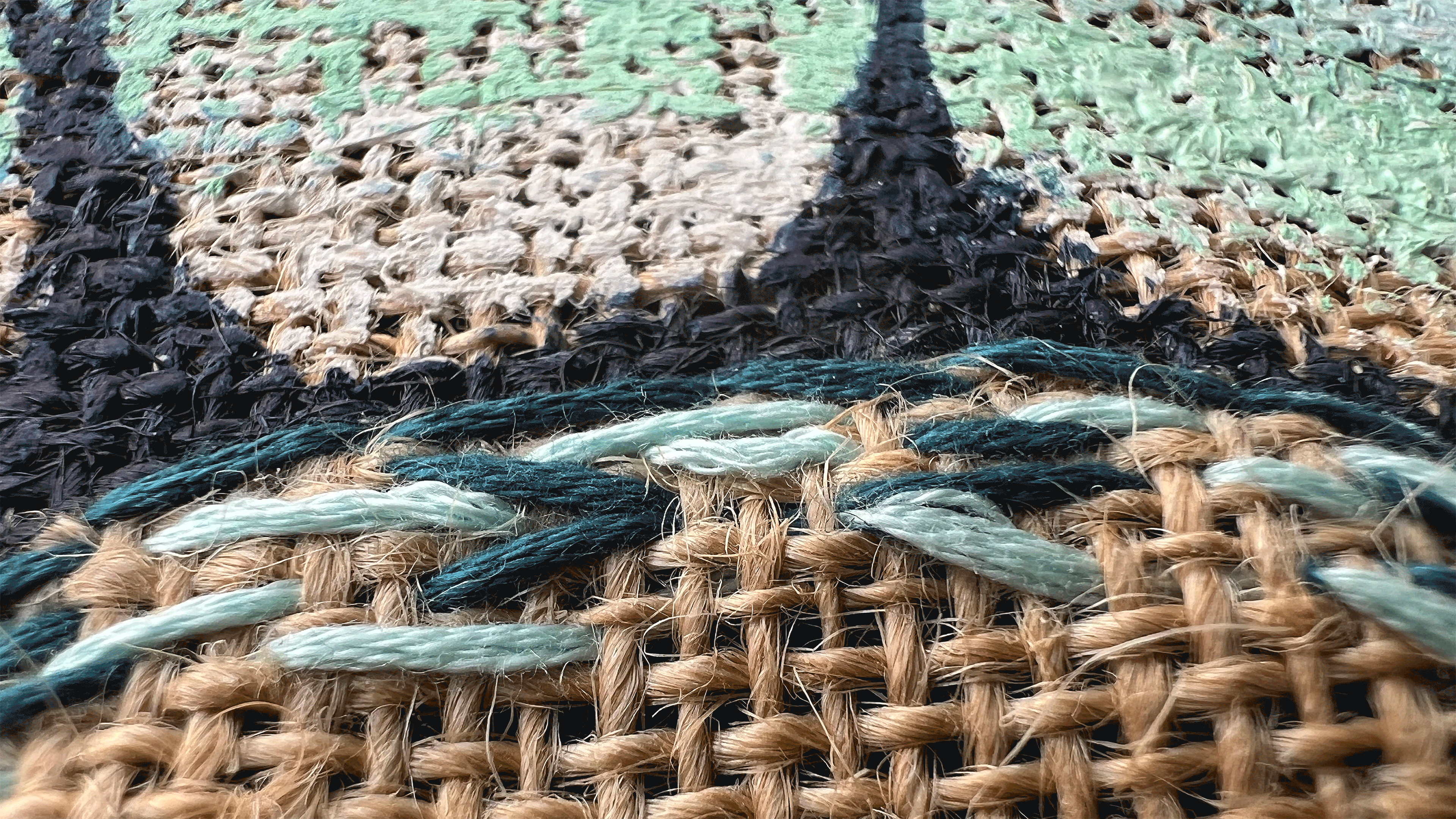 Detailaufnahme von Jutestoff mit Stickerei und Bemalung